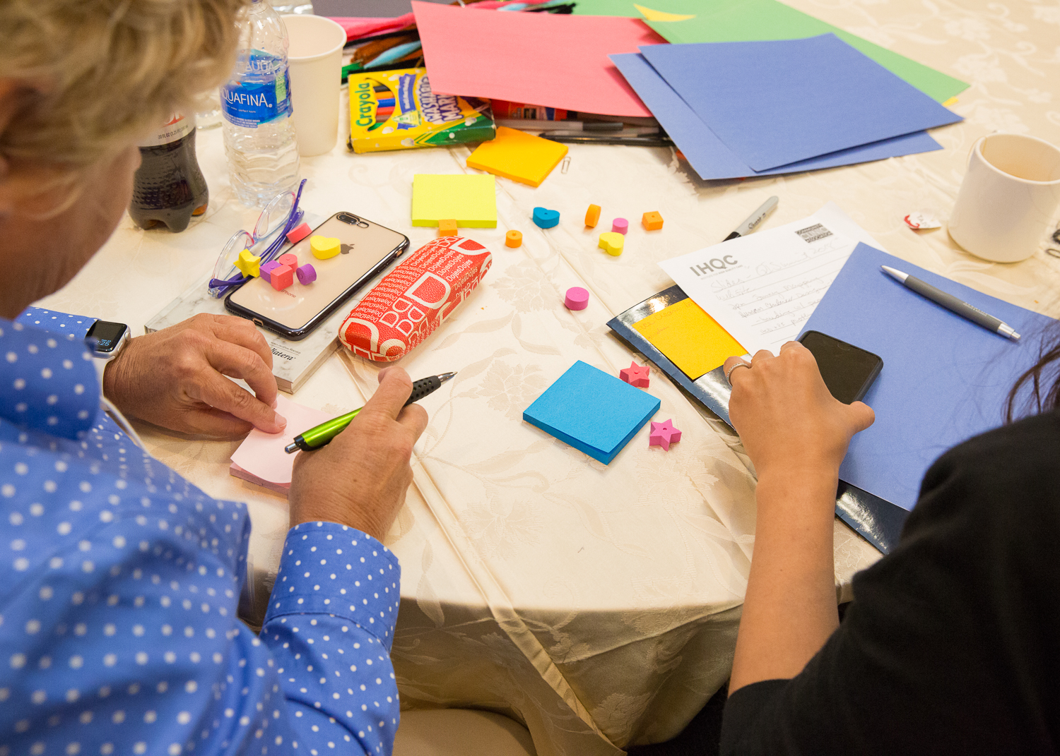 2 people sitting at a table with brightly-colored workshop materials